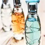 Three Assorted Clear Glass Perfume Spray Bottles on Brown Wooden Surface
