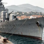 Navire de guerre de la Marine nationale amarré au port militaire de Toulon avec la rade en arrière-plan